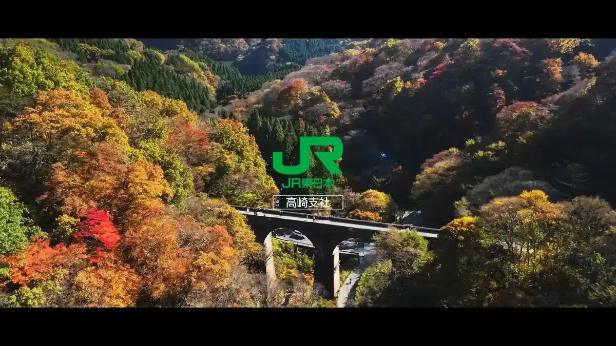 紅葉の谷を渡る鉄道橋と JR東日本のロゴ