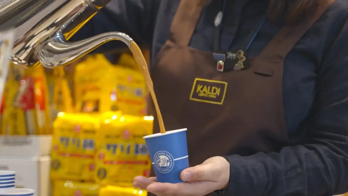 KALDI COFFEE FARM の店舗で商品を手に取るスタッフ。採用コンテンツのために撮影