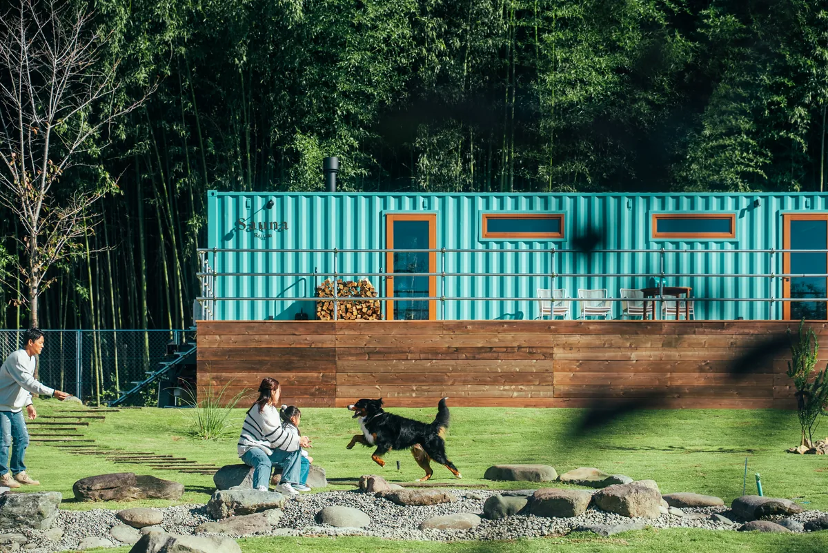竹林とコンテナサウナの前で遊ぶ家族と犬(THE W RELAX GARDEN RESORT)
